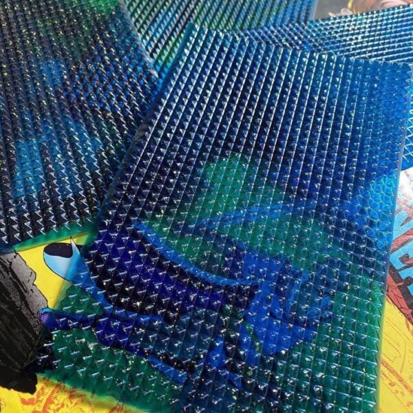 Translucent acid gel sheets with raised pyramid texture layered over vibrant comic book artwork in red, yellow, and blue tones"